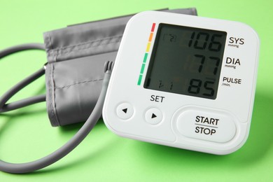 Photo of Blood pressure measuring device on green background, closeup