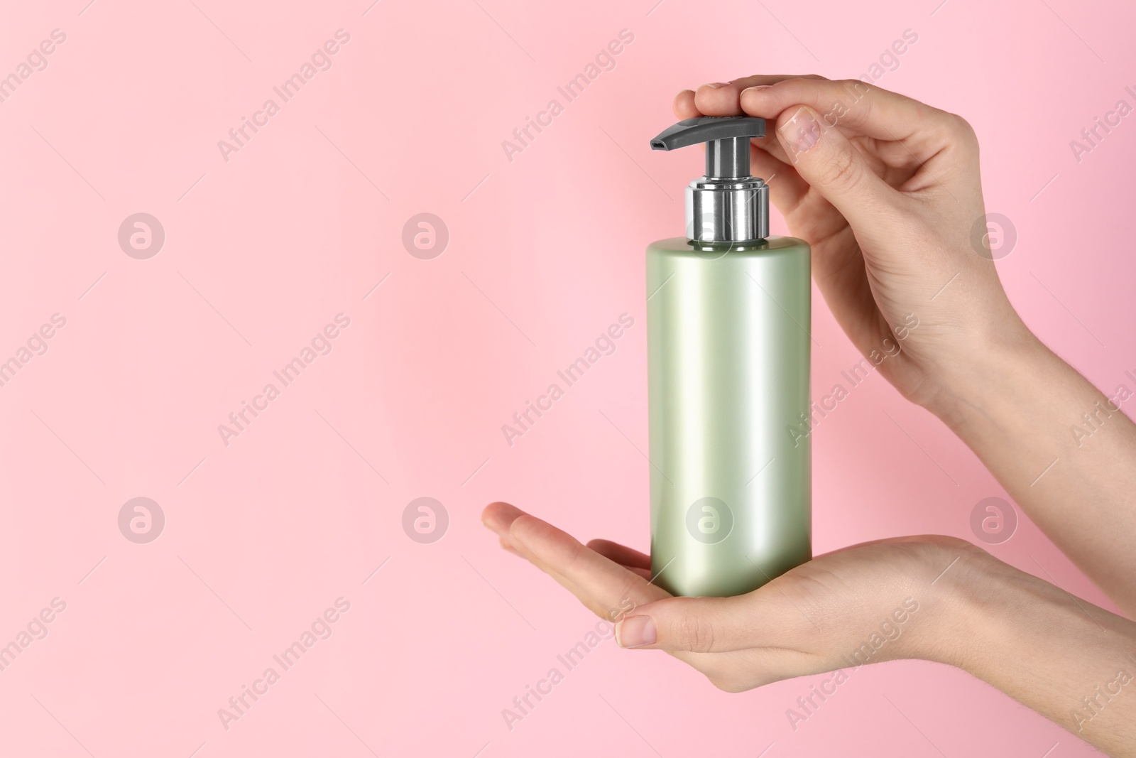 Photo of Woman with shampoo bottle on pink background, closeup. Space for text