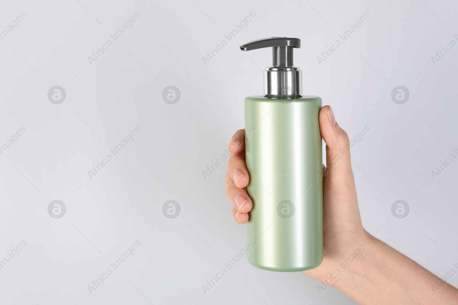 Photo of Woman with shampoo bottle on grey background, closeup. Space for text