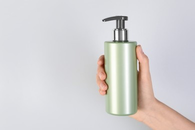 Photo of Woman with shampoo bottle on grey background, closeup. Space for text