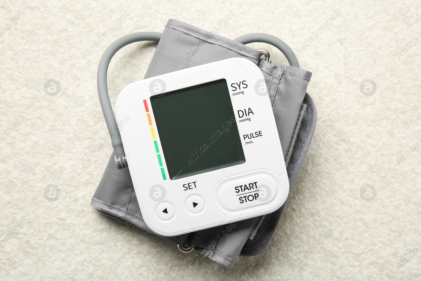 Photo of Blood pressure measuring device on light textured background, top view