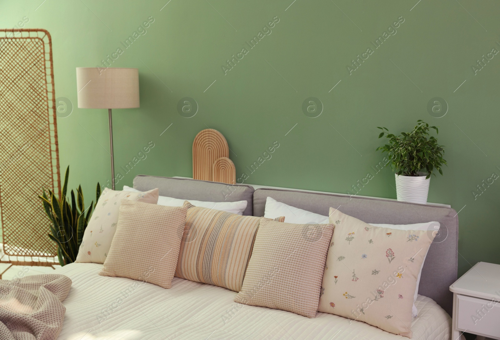 Photo of Stylish bedroom interior with large bed, houseplants and decorative elements