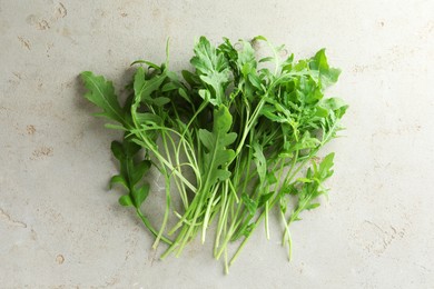 Photo of Many fresh arugula leaves on grey textured table, top view