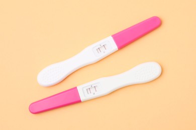 Photo of Pregnancy tests on pale orange background, above view