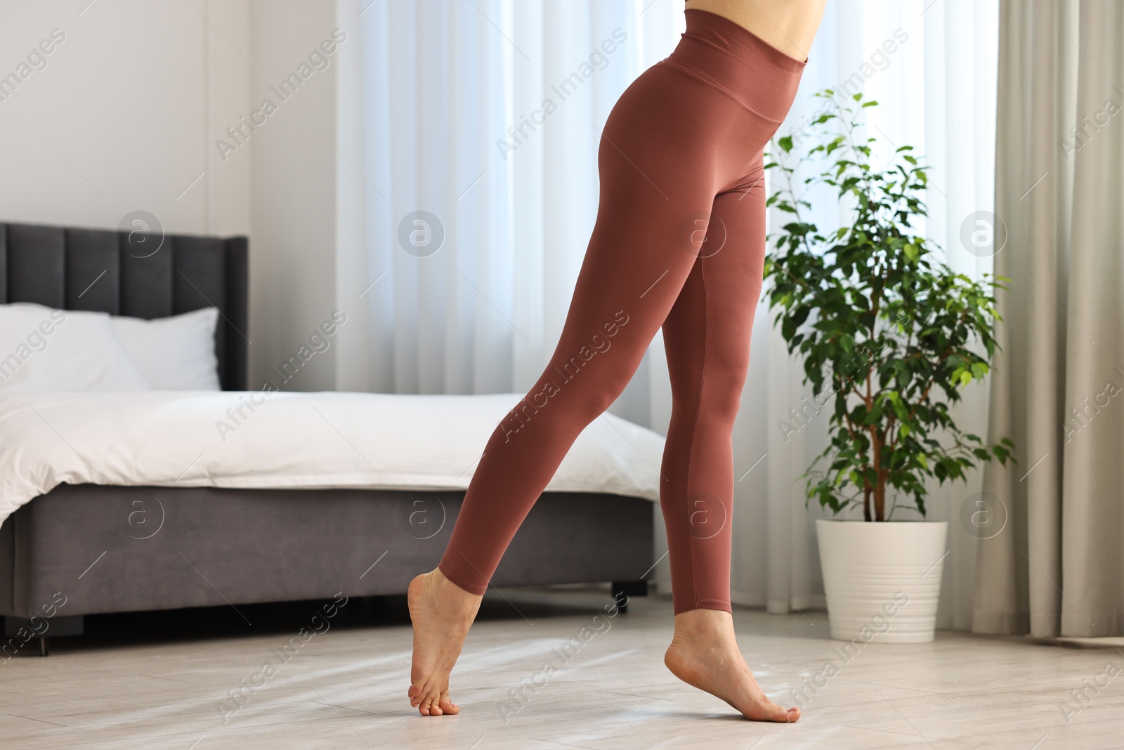 Photo of Woman wearing sports leggings in bedroom, closeup