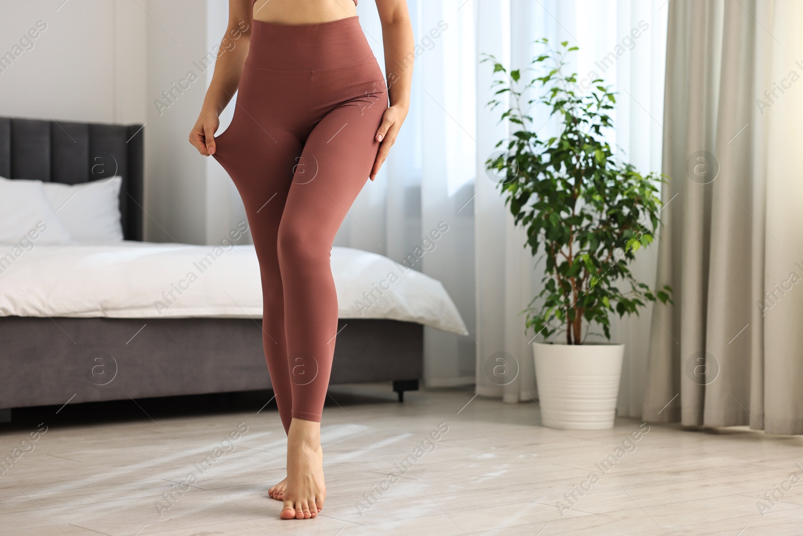 Photo of Woman wearing sports leggings in bedroom, closeup. Space for text