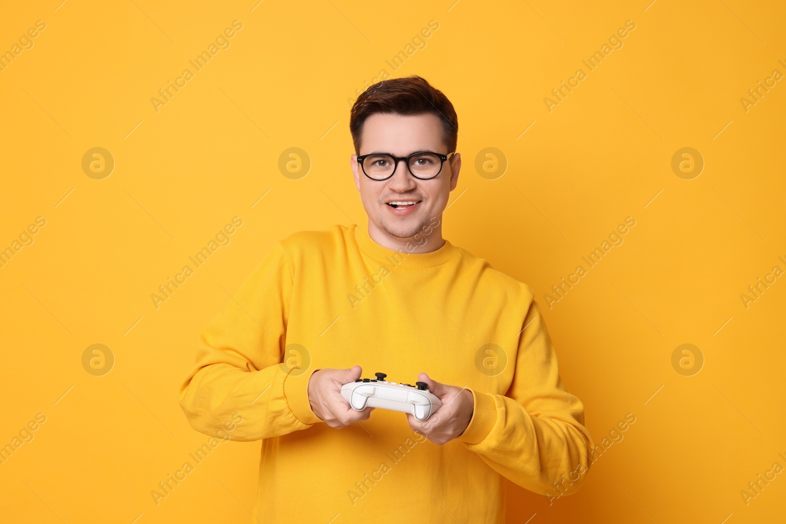 Photo of Happy young man playing video games with controller on orange background