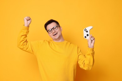 Young man with controller on orange background