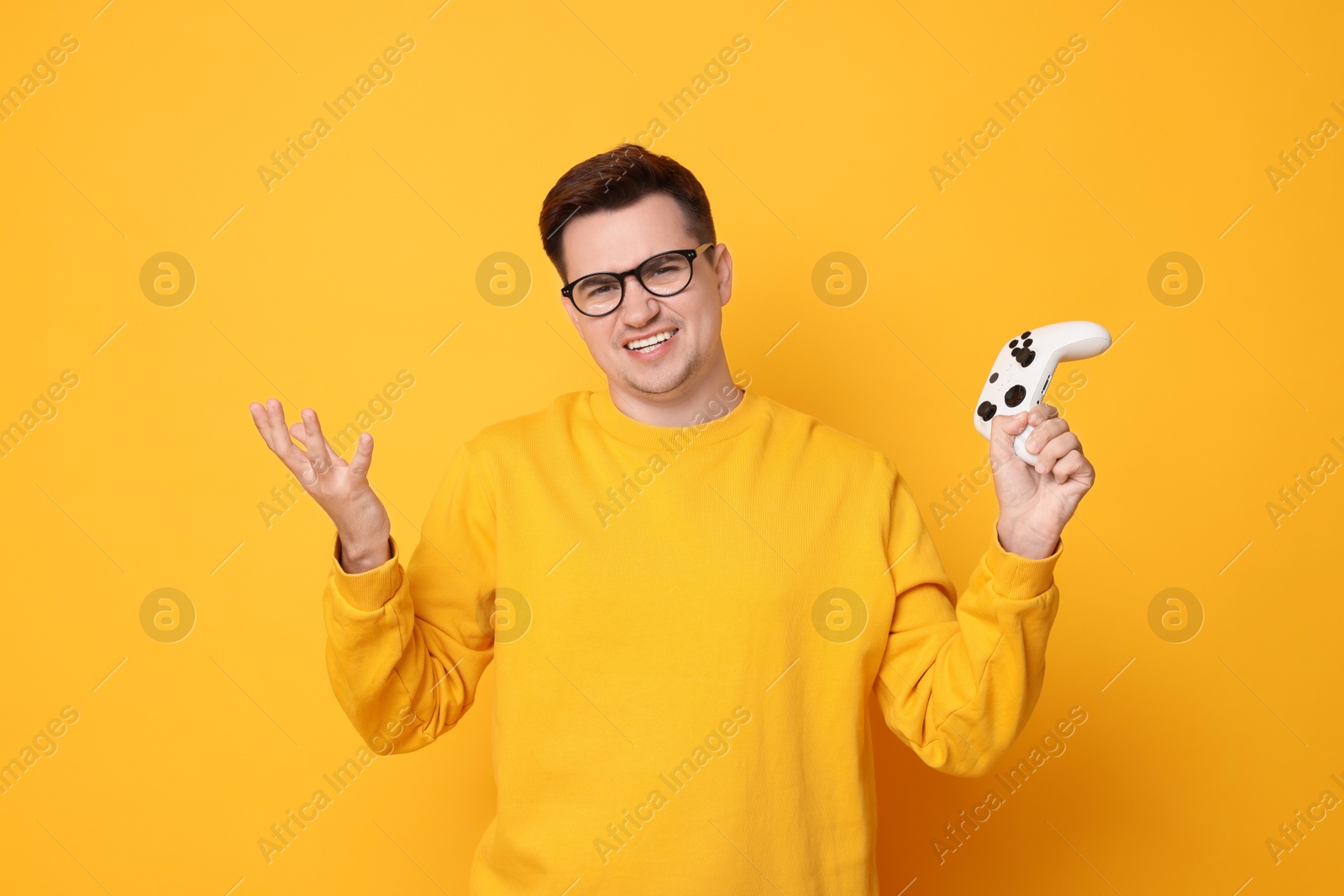 Photo of Unhappy young man with controller on orange background