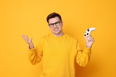 Unhappy young man with controller on orange background