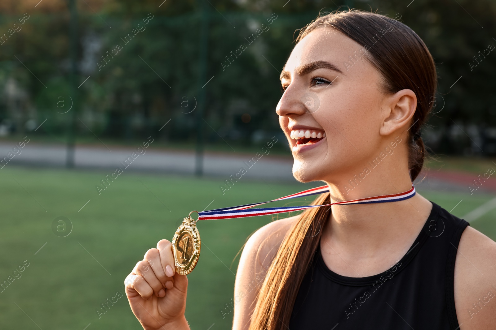 Photo of Happy winner with golden medal at stadium. Space for text