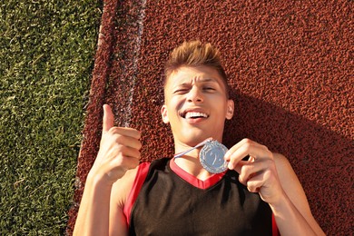 Happy winner with silver medal showing thumbs up at stadium