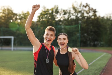 Portrait of happy winners with medals at stadium