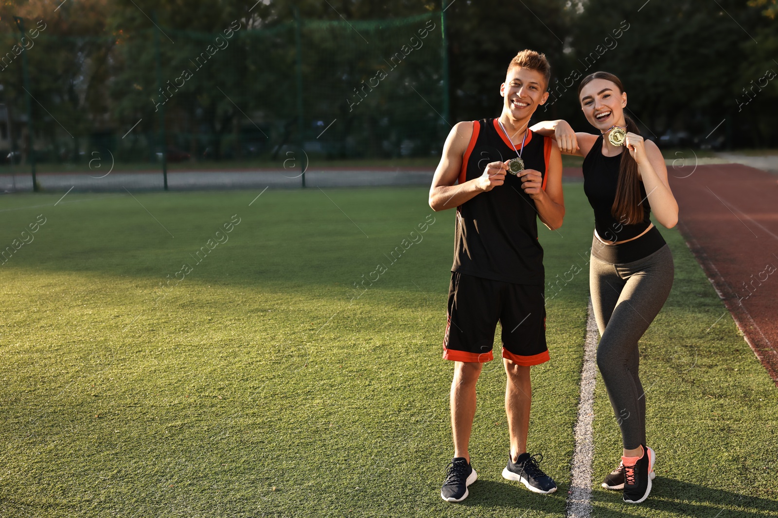 Photo of Happy winners with medals at stadium on sunny day. Space for text