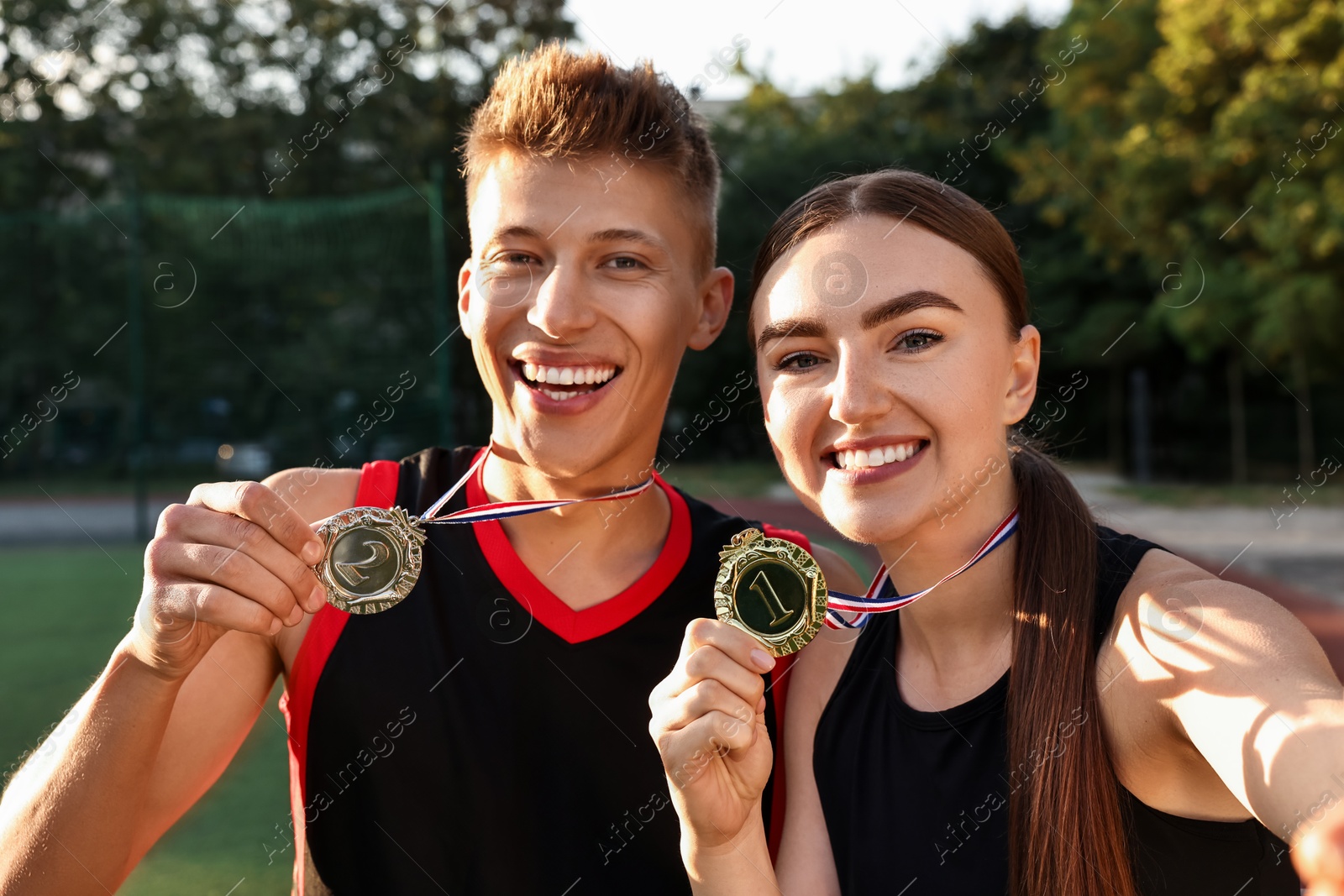 Photo of Happy winners with medals taking selfie at stadium