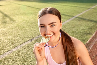 Happy winner with golden medal at stadium on sunny day. Space for text