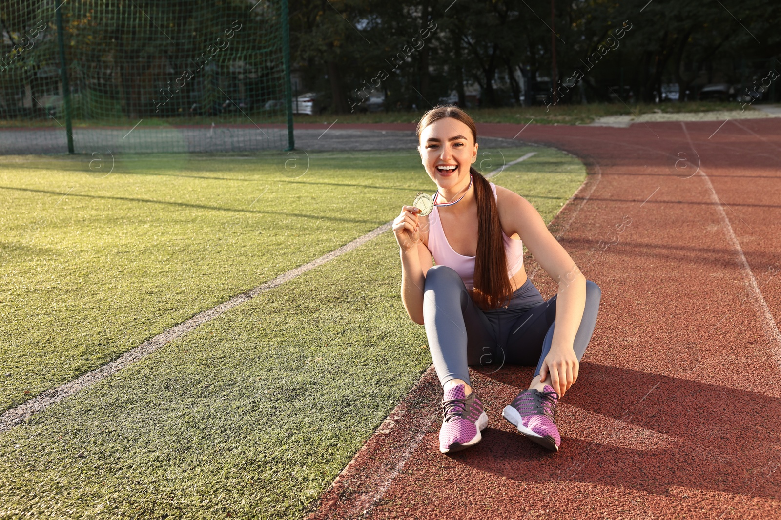 Photo of Happy winner with golden medal sitting at stadium on sunny day. Space for text