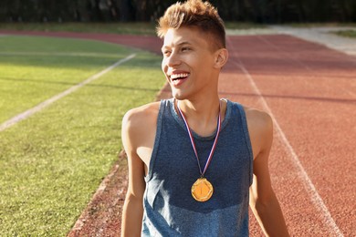 Happy winner with golden medal at stadium on sunny day