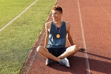 Happy winner with golden medal at stadium on sunny day