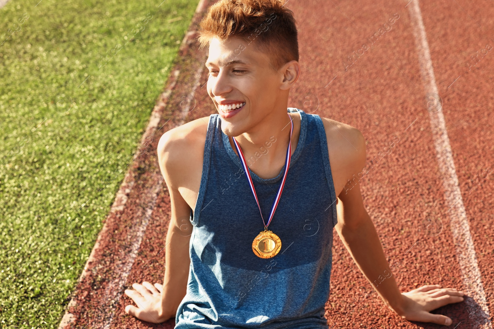 Photo of Happy winner with golden medal at stadium on sunny day