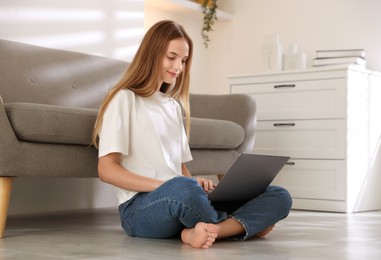 Photo of Teenage girl using laptop on floor at home