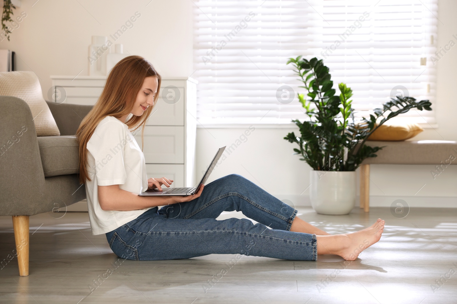 Photo of Teenage girl using laptop on floor at home