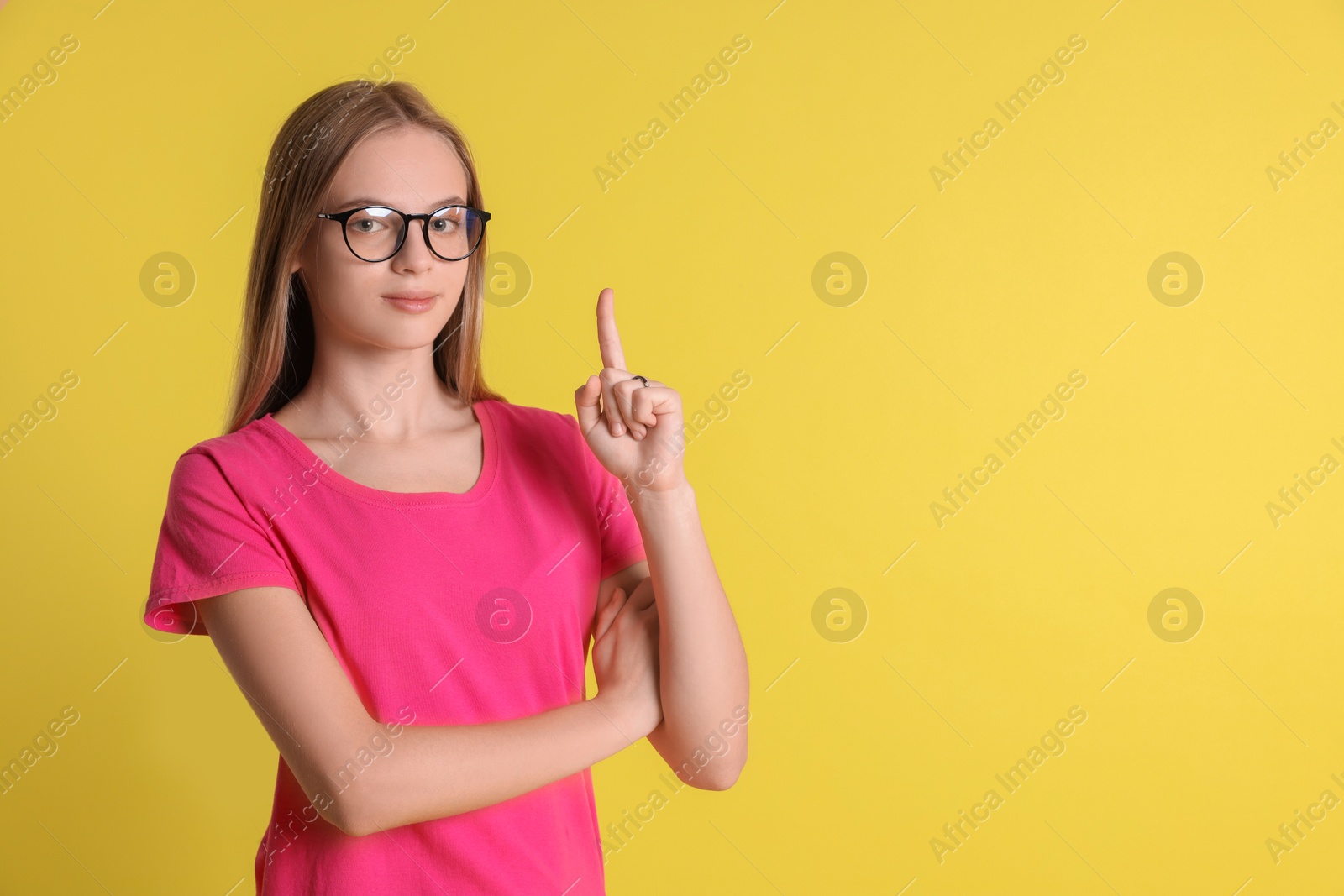 Photo of Portrait of teenage girl in glasses on yellow background, space for text