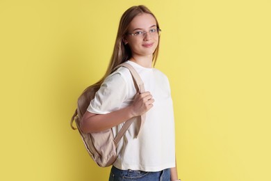 Photo of Teenage girl with backpack on yellow background