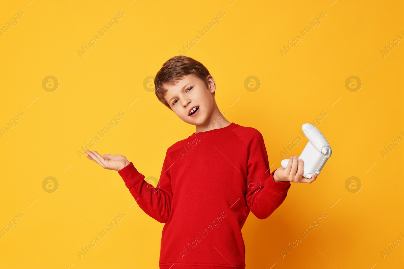 Photo of Cute little boy with controller on orange background