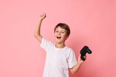 Photo of Happy little boy with controller on pink background