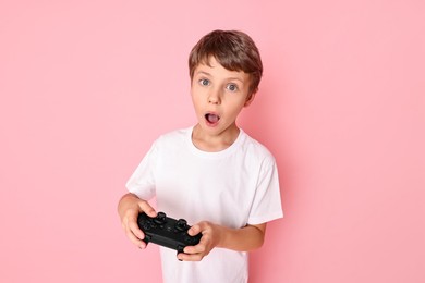 Photo of Cute little boy with controller on pink background