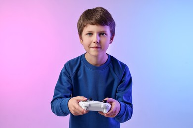 Photo of Cute little boy playing video game with controller on color background