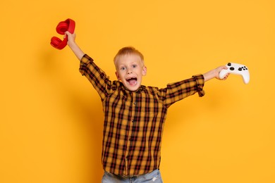 Photo of Happy little boy with controller and headphones on orange background