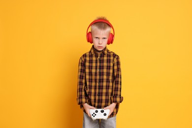 Little boy in headphones with controller on orange background