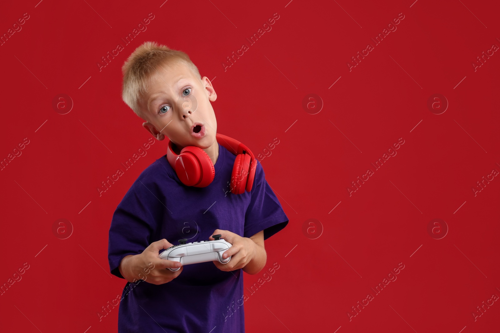 Photo of Cute little boy playing video game with controller on red background. Space for text