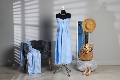 Female mannequin with stylish light blue dress and other clothes indoors