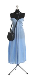 Photo of Female mannequin with light blue dress and black bag isolated on white