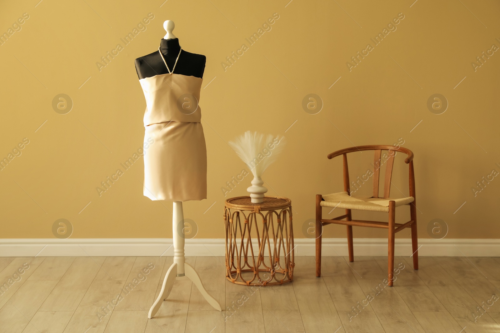 Photo of One female mannequin with unfinished dress, chair and coffee table in workshop