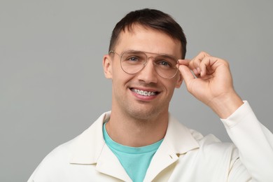 Photo of Smiling man with dental braces on grey background