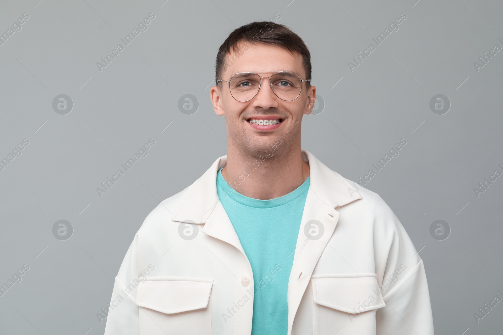 Photo of Smiling man with dental braces on grey background