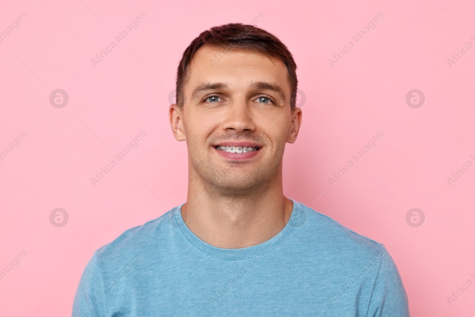 Photo of Smiling man with dental braces on pink background