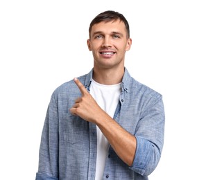 Photo of Smiling man with dental braces pointing at something on white background