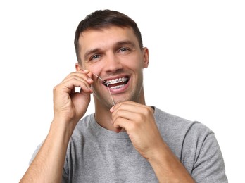 Man with braces cleaning teeth using dental floss on white background