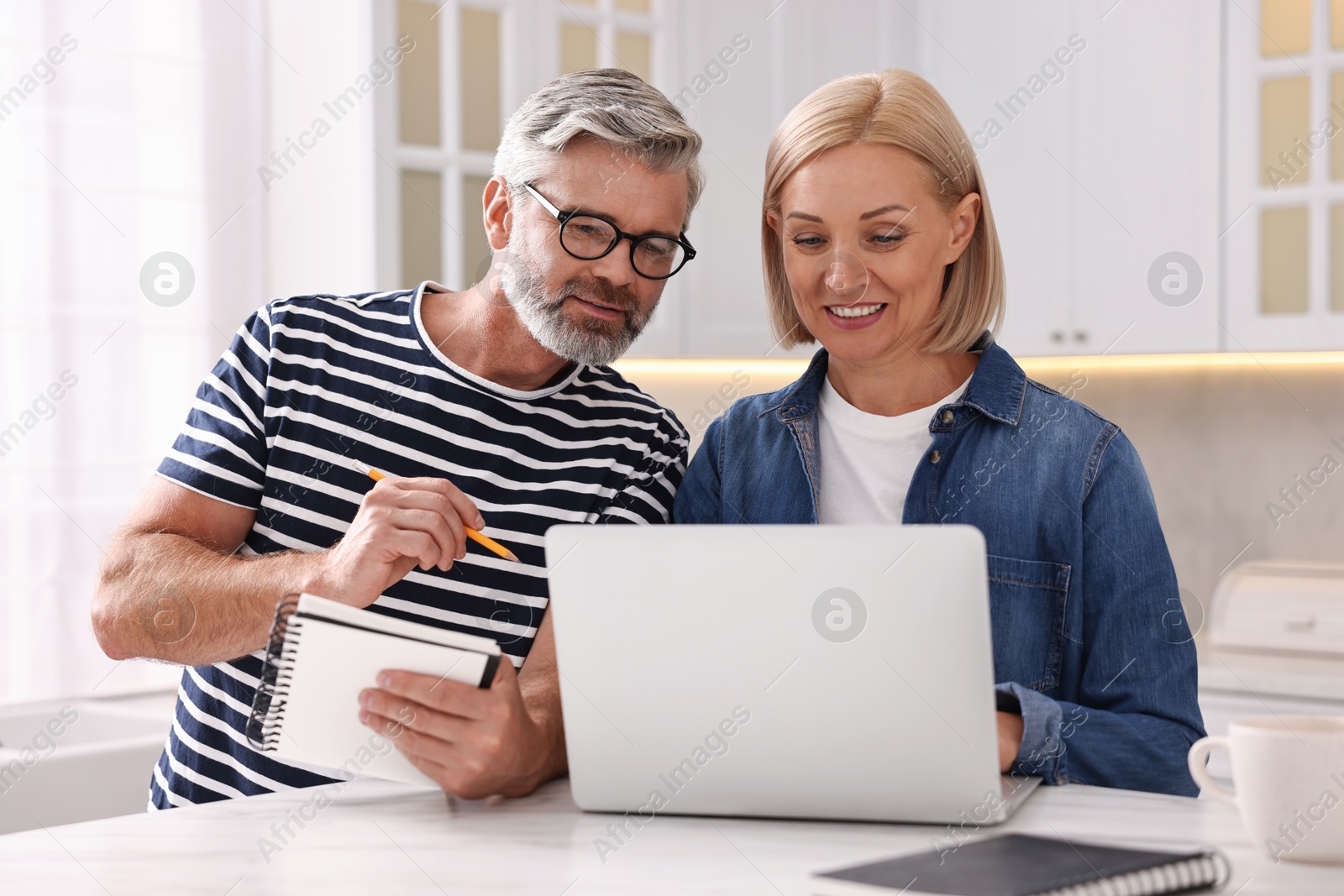 Photo of Middle aged couple working at white marble table in kitchen