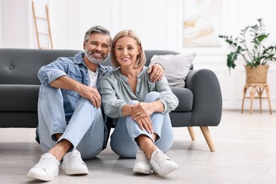 Portrait of happy middle aged couple on floor at home