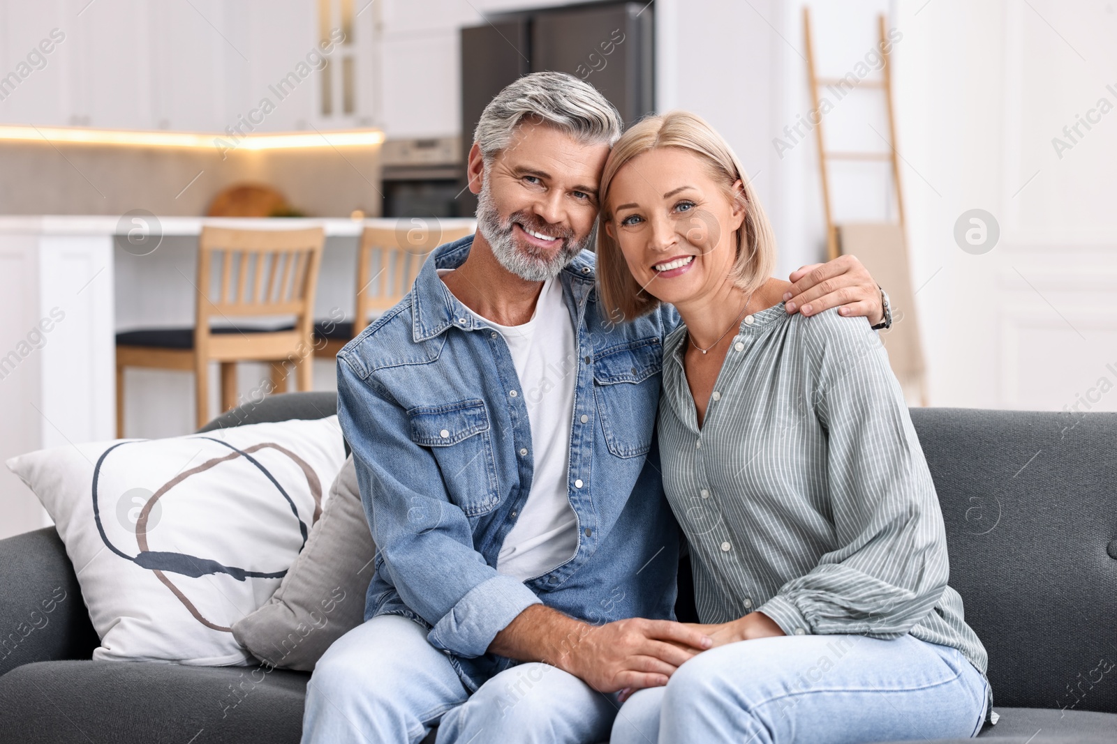 Photo of Portrait of happy middle aged couple on sofa in kitchen