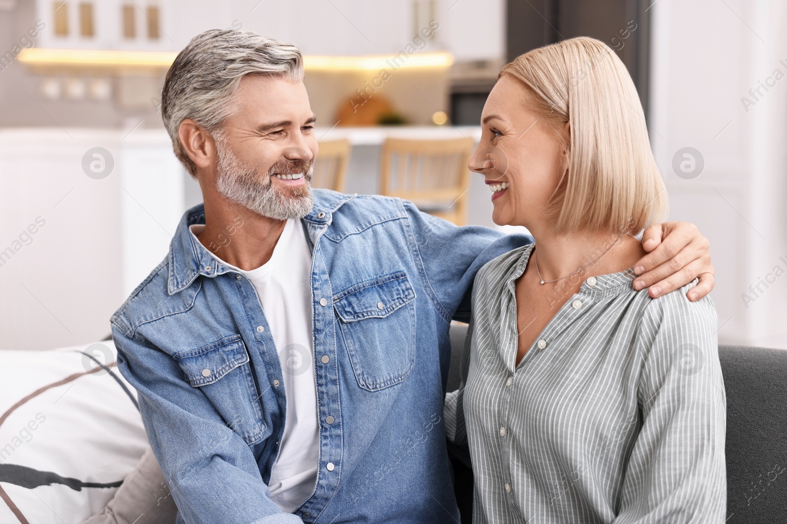 Photo of Happy middle aged couple on sofa in kitchen