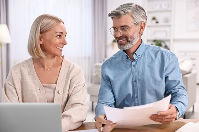 Photo of Happy middle aged couple working at table indoors