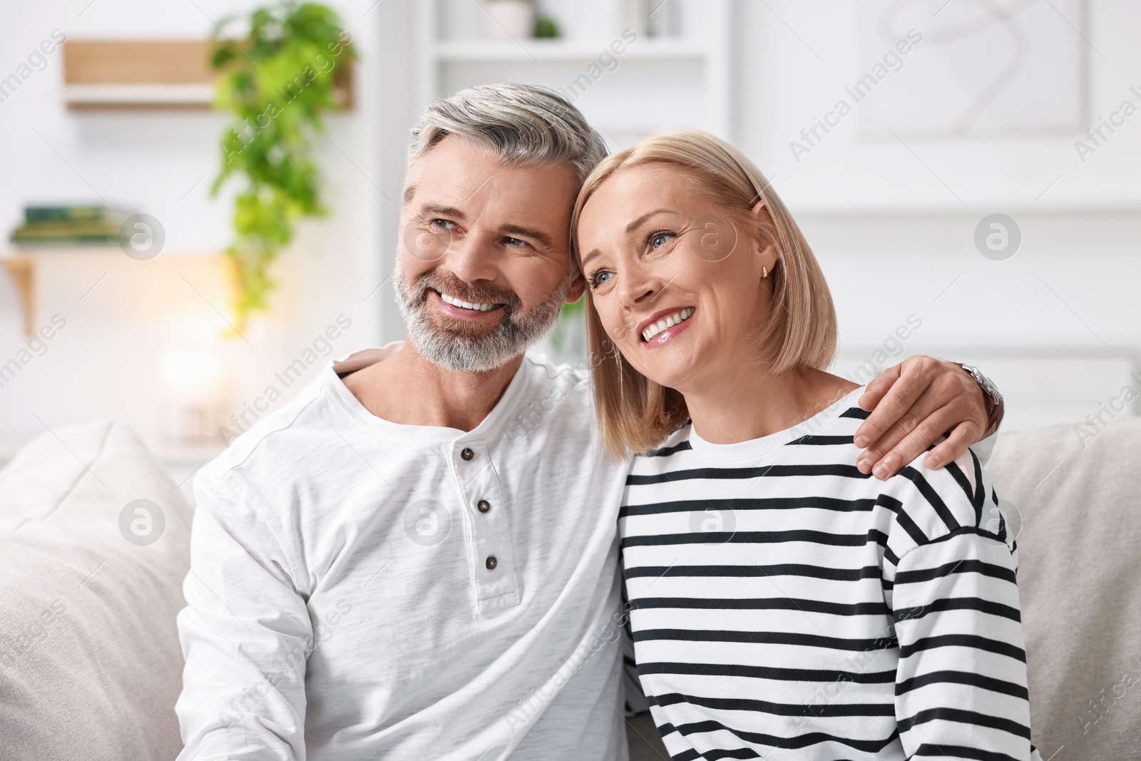 Photo of Happy middle aged couple on sofa at home