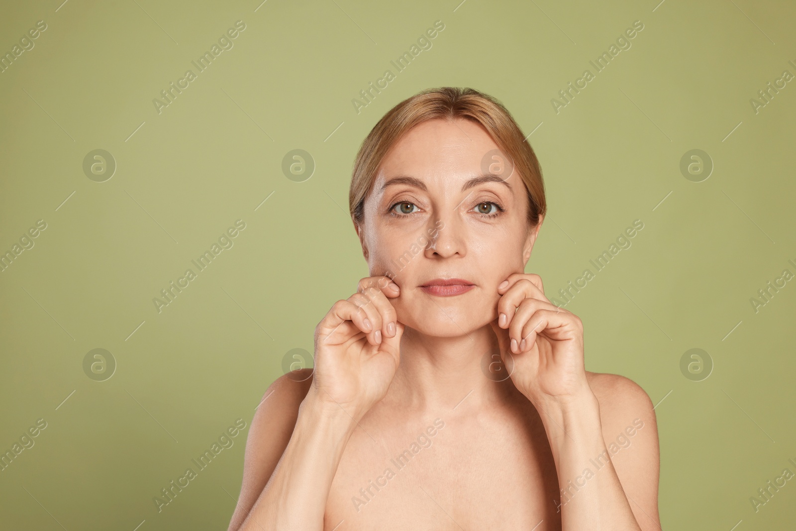 Photo of Beautiful woman doing facial self massage on green background